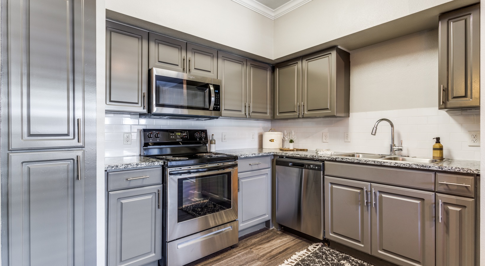 a kitchen with stainless steel appliances and gray cabinets at The Ellwood at Lake Travis