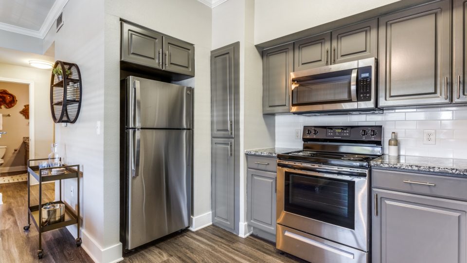 a kitchen with stainless steel appliances and wood floors at The Ellwood at Lake Travis