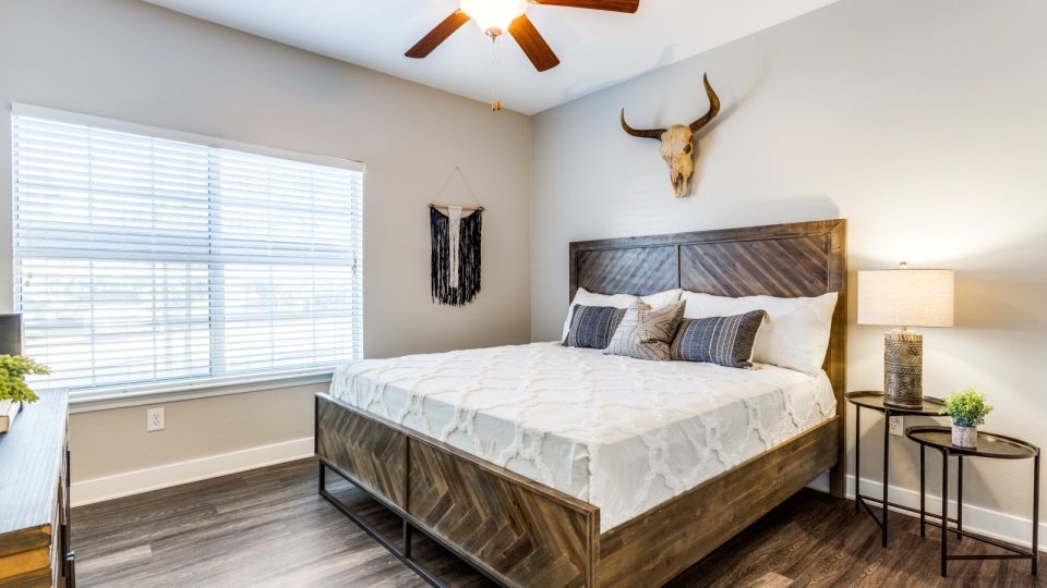 a bedroom with a wooden bed and ceiling fan at The Ellwood at Lake Travis
